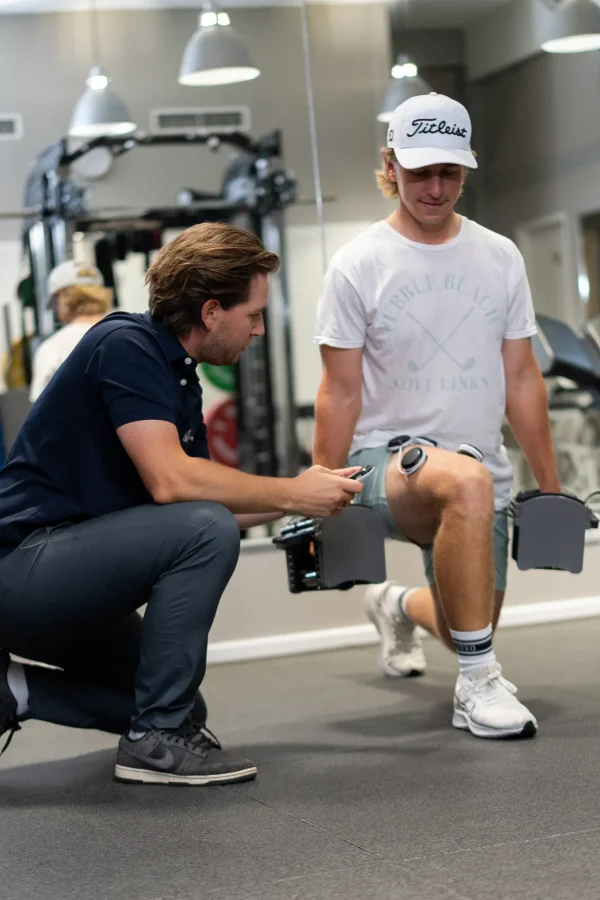 Physiotherapeut stellt die Compex-Elektrostimulation am Knie während eines Ausfallschritts ein