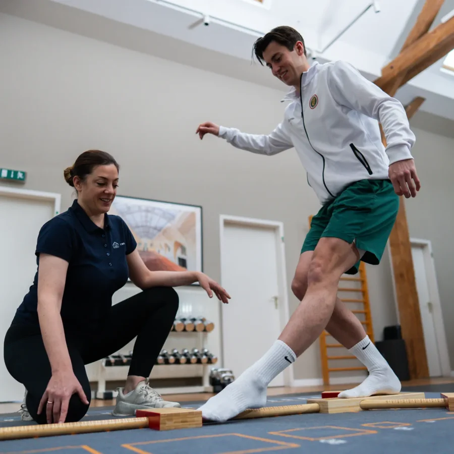 Physiotherapeutin begleitet einen Sportler beim Y-Balance-Test zur Gleichgewichtsmessung